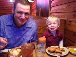 A very happy little boy sitting by his daddy.